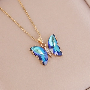 Macro shot of gold butterfly pendant with blue-green gradient crystals and diamonds