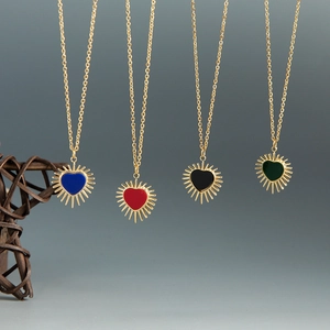 Dettaglio di ciondoli a cuore in smalto blu rosso nero e verde con raggi dorati lucidi