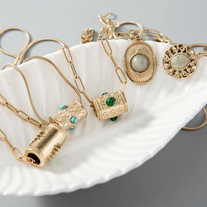 Détails de colliers dorés vintage avec accents turquoise et breloques texturées sur plateau
