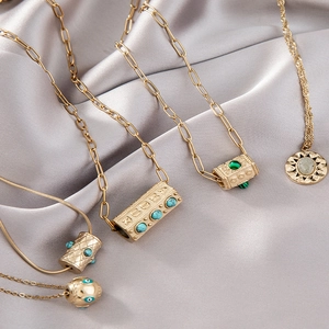 Ensemble de cinq colliers en acier titane doré avec pendentifs turquoise et œil