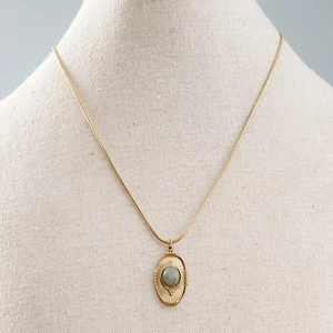 Gros plan sur le collier vintage doré avec pendentif ovale turquoise et chaîne serpent