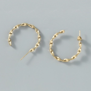 Macro detail of golden twisted geometric hoop earrings with polished spiral texture