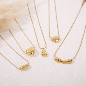 Colliers dorés minimalistes avec pendentifs cœur et formes géométriques sur fond blanc