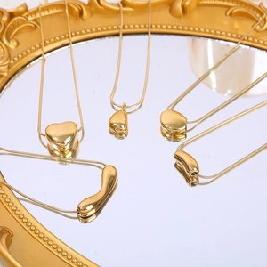 Colliers dorés avec pendentifs cœur et chaîne serpent présentés sur un miroir vintage