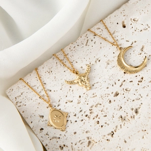 Detailed set of gold necklaces with crescent moon, bull head and starburst pendant charms