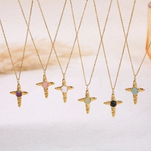 Golden cross necklaces with six natural stone colors on a textured beige surface