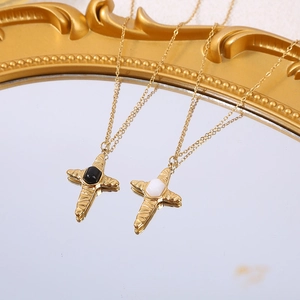 Close-up of gold cross necklaces with hammered texture and black and white stone inlays