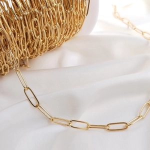 Vue macro de maillons de chaîne dorés ovales sur soie blanche pour bijoux DIY