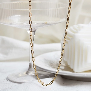 Élégant collier à maillons trombones dorés présenté avec un décor de luxe minimaliste