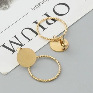 Elegant gold twisted hoop earrings with brushed metal studs on a minimalist background