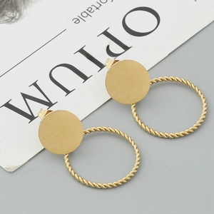 Minimalist matte gold twisted hoop earrings with brushed metal disks on a white card