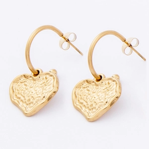 Detailed macro view of gold heart dangle earrings with vintage hammered metal texture
