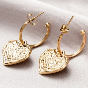 Detailed view of gold twisted hoop earrings with textured heart charms and butterfly backs