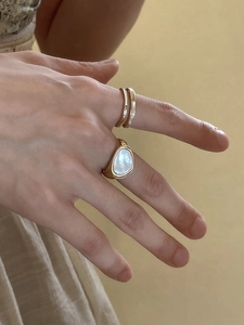 Detail of emerald design gold ring set with white mother of pearl inlay on woman's hand