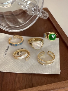 Close-up of five-piece vintage gold ring set with emerald gems and enamel details