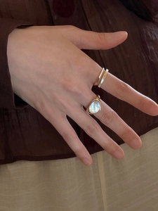 Detail of layered gold rings featuring a large teardrop gemstone and thin textured bands
