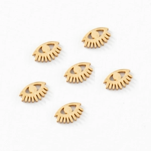 Gros plan de six breloques yeux dorées avec cils pour la création de bijoux DIY