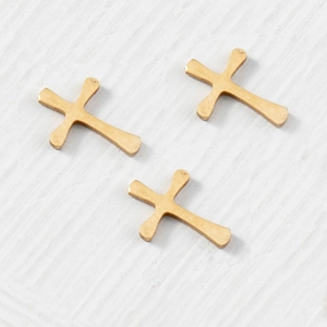 Trois pendentifs croix dorés mats sur un fond de papier blanc texturé élégant