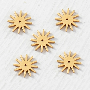 Détail de cinq pendentifs dorés en forme d'étoile sur un fond de bois blanc doux