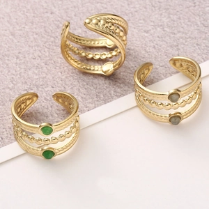 Detail of layered gold-plated titanium steel rings with green and grey natural stones