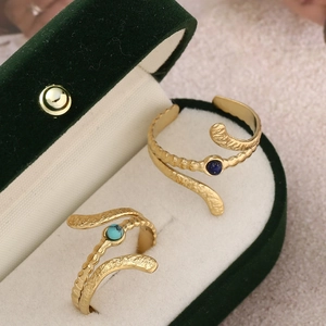 Close-up of gold snake rings with lapis lazuli and turquoise in a velvet box