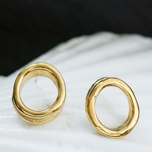 Macro shot of gold irregular oval stud earrings with handcrafted hammered texture finish