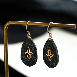 Close-up of vintage teardrop earrings with marble texture and golden star inlay