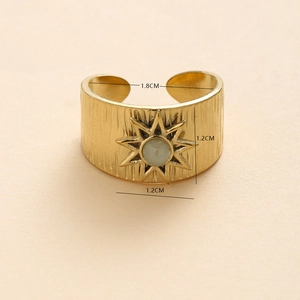 Detail of vintage gold wide flower ring featuring starburst pattern and green natural stone
