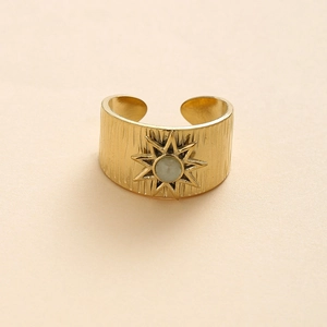Wide gold-tone steel ring with brushed texture, sunburst motif and green stone
