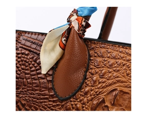 Detalle de bolso de cuero marrón con textura de cocodrilo y pañuelo de seda colorido