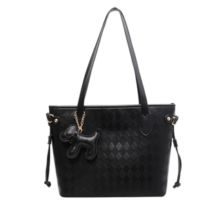 Detail of black quilted tote bag with textured diamond pattern and cute puppy charm
