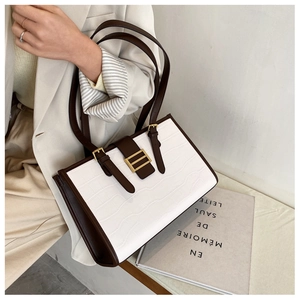 Detail of French tote bag with cream crocodile texture and dark brown leather straps