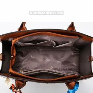 Vista interior del bolso marrón con diseño de cocodrilo y compartimentos con cremallera