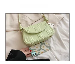 Detail of light green PU leather bag with biscuit pattern next to phone for size scale