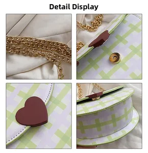 Detail view of plaid saddle bag featuring brown heart buckle and golden chain strap