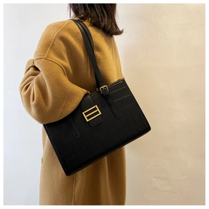 Detailed close-up of black crocodile pattern tote bag with gold metal buckle and strap