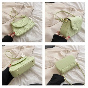 Detail view of light green bag showing bear embossing, knotted strap and metal studs