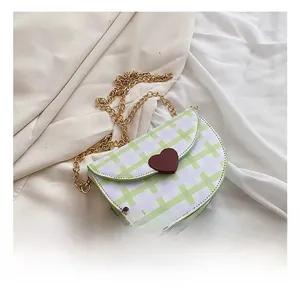 Detail showing green checkered saddle bag with golden chain and heart charm