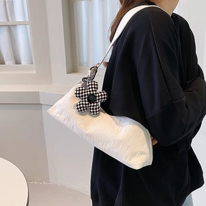 Minimalist white textured underarm bag with checkerboard flower charm worn on shoulder