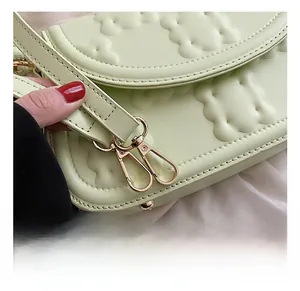 Detail of high-quality gold hardware and mint green textured leather on a chic shoulder bag