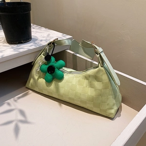 Minimalist green checkerboard hobo bag with flower pendant shown in lifestyle setting
