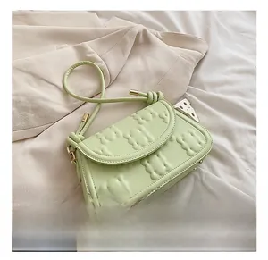 Detail of light green bag with biscuit texture, cheese charm and gold hardware