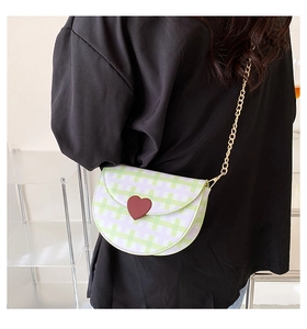 Close-up of green and purple plaid saddle bag with red heart clasp and gold chain