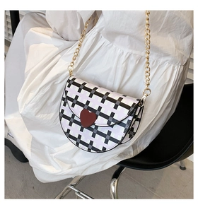 Detail of checkered saddle bag with red heart buckle and golden chain strap on model