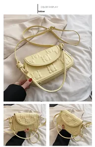 Close-up detail of yellow baguette bag featuring embossed cartoon bear patterns