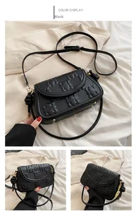 Detail of black leather bag with embossed bear pattern and golden metal hardware