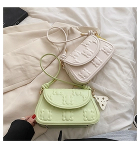 Close-up of cream and light green PU bags featuring embossed bear patterns and dot charms