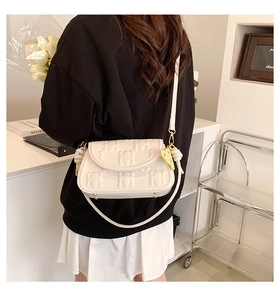 Detail of cream shoulder bag featuring embossed bear texture and yellow heart charm