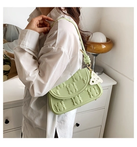 Detail showing the light green faux leather shoulder bag with textured cloud pattern and knot
