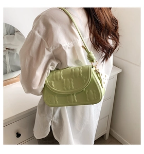 Detail of pistachio green leather bag with embossed bear pattern and gold hardware